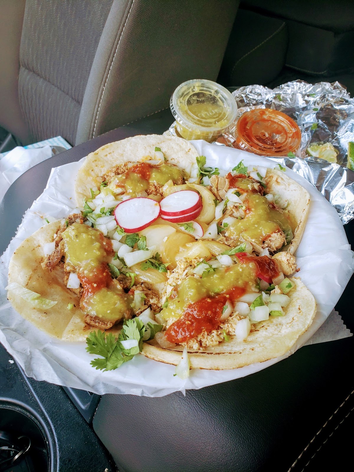 A platter of chicken street tacos with radish, onion, cilantro, red and green salsa and lime
