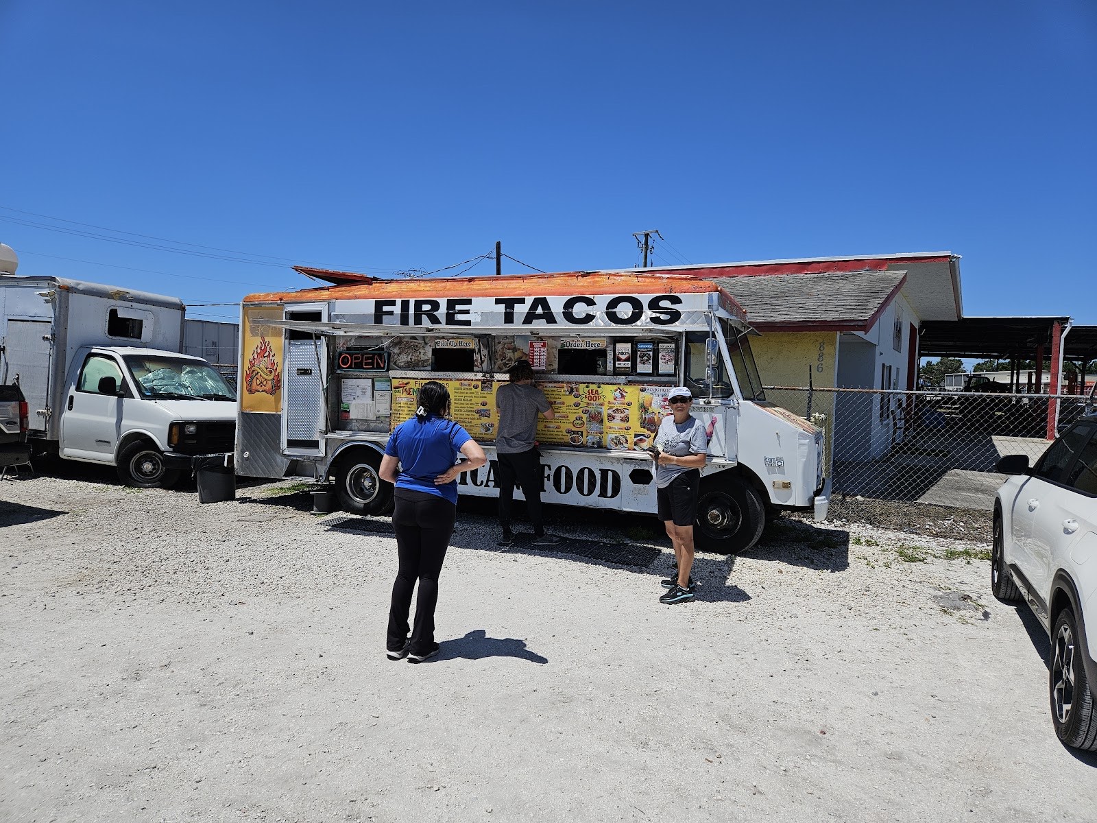 Customers lined up at the Fire Tacos truck window on a sunny Sarasota afternoon
